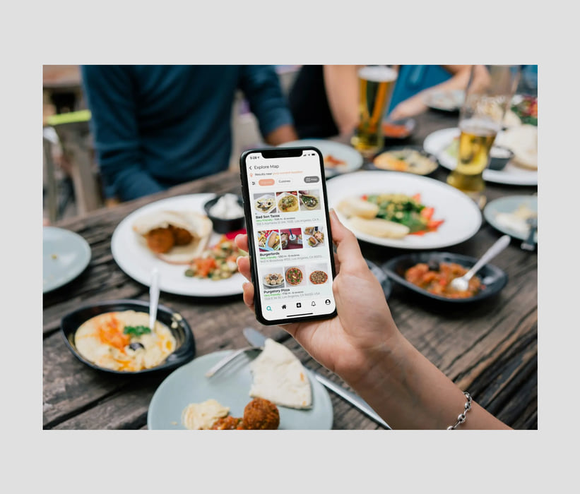 Choosing where to eat on a phone at a shared table of food